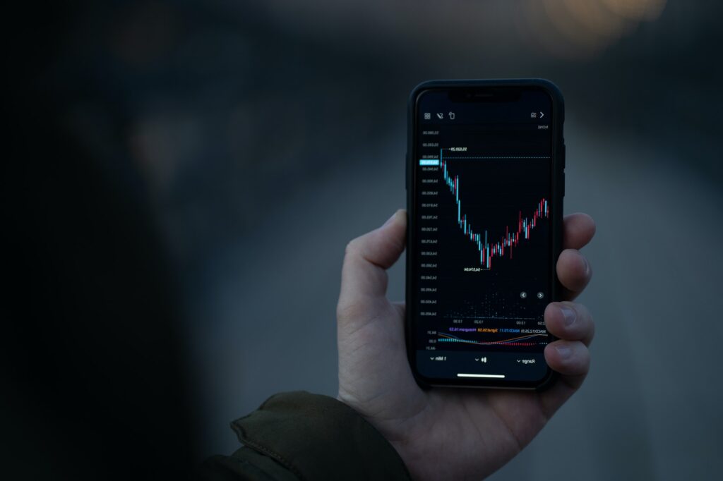 Male hand holding smartphone with real time forex chart on screen